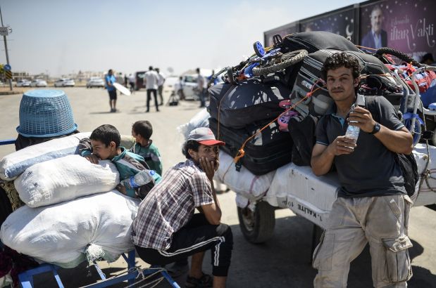 Syrian refugees wait with their belongings prior to go back to the northern Syrian town of Tal Abyad at the Turkish border post of Akcakale, the province of Sanliurfa, on June 17, 2015. The first Syrian refugees returned to the border town of Tal Abyad from Turkey after it was liberated from the Islamic State (IS) group, an AFP journalist reported.  Kurdish forces took the strategic town on Tuesday after several days of intense fighting, which sparked an exodus of more than 23,000 refugees into neighbouring Turkey. AFP PHOTO / BULENT KILIC