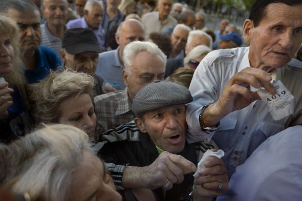Pensioners holding their queue numbers try to enter into a bank in Athens, Wednesday, July 1, 2015. About 1,000 bank branches around the country were ordered by the government to reopen Wednesday to help desperate pensioners without ATM cards cash up to 120 euros (4) from their retirement checks. Eurozone finance ministers were set to weigh Greece's latest proposal for aid Wednesday. (AP Photo/Daniel Ochoa de Olza)