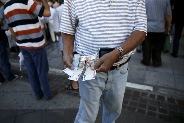 A pensioner shows the part of his pension he received outside a National Bank branch in Athens, Greece, July 1, 2015. About one thousand Bank branches around Greece opened on Wednesday to allow pensioners to receive a small part of their benefits. Greece's last-minute overtures to international creditors for financial aid on Tuesday were not enough to save the country from becoming the first developed economy to default on a loan with the International Monetary Fund. REUTERS/Alkis Konstantinidis