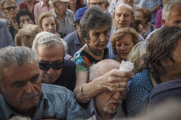 Pensioners crowd the entrance of bank in Athens, Wednesday, July 1, 2015. Long lines formed as bank branches around the country were ordered by Greece's government to reopen Wednesday to help desperate pensioners without ATM cards cash up to 120 euros (4) from their retirement checks. (AP Photo/Daniel Ochoa de Olza)