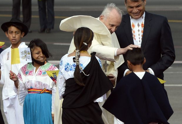 Pope Francis (L), accompanied by Ecuadorean President Rafael Correa, is welcomed by children dressed in traditional attire as he arrives at the Mariscal Sucre international airport in Quito on July 5, 2015. Pope Francis arrived in Quito Sunday to begin his first South American trip in two years, for an eight-day tour of Ecuador, Bolivia and Paraguay highlighting the plight of the poor on his home continent. AFP PHOTO / JUAN CEVALLOS