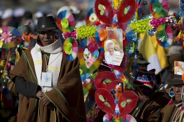 A man stands by a large decorative cross decorated with a picture of Pope Francis as he waits for the pope's arrival at El Alto International airport in El Alto, Bolivia, Wednesday, July 8, 2015. Due to the altitude, the pontiff will spend only a few hours in the capital city La Paz, which is near El Alto, during his South American tour. (AP Photo/Eduardo Verdugo)