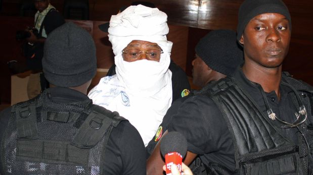 Security personnel surround former Chadian dictator Hissene Habre inside the court in Dakar, Senegal, Monday, July 20, 2015. The trial of former Chadian dictator Hissene Habre, accused of overseeing the deaths of thousands, had a chaotic beginning Monday as security forces ushered the ex-leader into and then out of the Senegal courtroom amid protests by his supporters.(AP Photo/Sophiane Bengeloun)