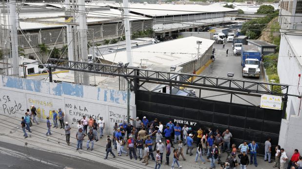 People gather at the main gate of a facility used by Empresas Polar as a distribution center, during the occupation of its installations by government representatives in Caracas July 30, 2015. REUTERS/Carlos Garcia Rawlins