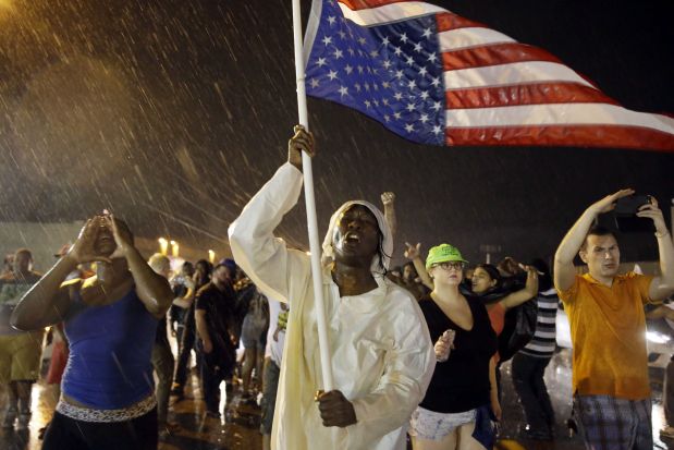 Protesters march in the rain, Sunday, Aug. 9, 2015, in Ferguson, Mo. Sunday marks one year since Michael Brown was shot and killed by Ferguson Police Officer Darren Wilson. (AP Photo/Jeff Roberson)