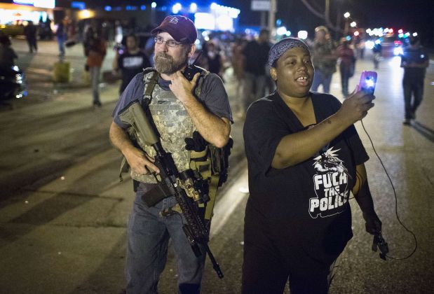 FERGUSON, MO - AUGUST 10: A demonstrator, marking the one-year anniversary of the shooting of Michael Brown, confronts an Oath Keeper during a protest along West Florrisant Street on August 10, 2015 in Ferguson, Missouri. Mare than 100 people were arrested today during protests in Ferguson and the St. Louis area. Brown was shot and killed by a Ferguson police officer on August 9, 2014. His death sparked months of sometimes violent protests in Ferguson and drew nationwide focus on police treatment of black offenders.   Scott Olson/Getty Images/AFP== FOR NEWSPAPERS, INTERNET, TELCOS & TELEVISION USE ONLY ==