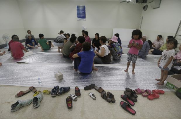South Korean residents gather at a shelter in the South Korean town of Yeoncheon where the shell fell  Thursday, Aug. 20, 2015. South Korea's military fired dozens of shells Thursday at rival North Korea after the North lobbed a single artillery round at the border town, the South's Defense ministry said. (AP Photo/Ahn Young-joon)