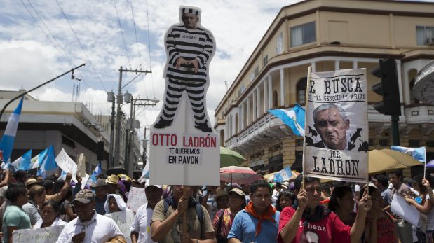A demonstrator, holding a cutout of Guatemala's President Otto Perez Molina dressed in prison stripes with a message that reads in Spanish: