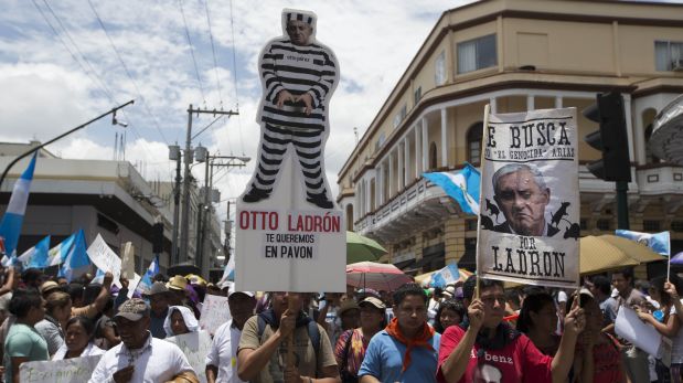 A demonstrator, holding a cutout of Guatemala's President Otto Perez Molina dressed in prison stripes with a message that reads in Spanish: 