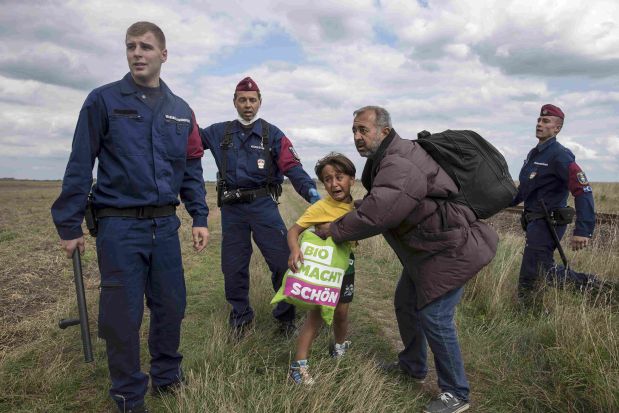 Hungarian policemen attempt to stop a migrant and a child to run from a collection point in Roszke village, Hungary, September 8, 2015. REUTERS/Marko Djurica