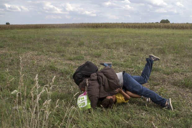 A migrant falls over a child as he tries to escape from a collection point in Roszke village, Hungary, September 8, 2015. REUTERS/Marko Djurica