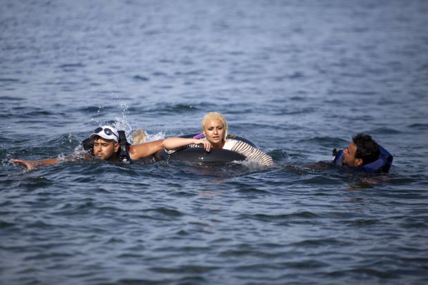 Syrian refugees swim towards a beach after abandoning a dinghy with a broken engine on the Greek island of Lesbos, September 9, 2015. Greece asked the European Union for aid to prevent it being overwhelmed by refugees, as a minister said arrivals on Lesbos had swollen to three times as many as the island could handle.  REUTERS/Dimitris Michalakis