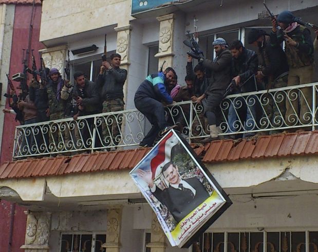 Free Syrian Army fighters from Al-Farooq battalion remove a poster of Syria's President Bashar Al-Assad from a military hospital after the fighters said they fought and defeated government troops in Halfaya, near Hama December 18, 2012.   REUTERS/Samer Al-Hamwi/Shaam News Network/Handout (SYRIA - Tags: CONFLICT TPX IMAGES OF THE DAY) FOR EDITORIAL USE ONLY. NOT FOR SALE FOR MARKETING OR ADVERTISING CAMPAIGNS