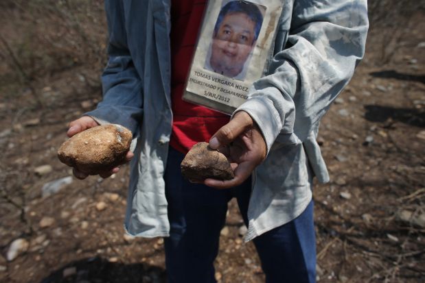 In this April 22, 2015 photo, Mario Vergara explains how the pigmentation of rocks helps him as he looks for clandestine graves amidst dry vegetation on the outskirts of Iguala, Mexico. Vergara says that some stones have the look of having been recently unearthed in the digging of a grave rather than always having been on the surface. (AP Photo/Dario Lopez-Mills)