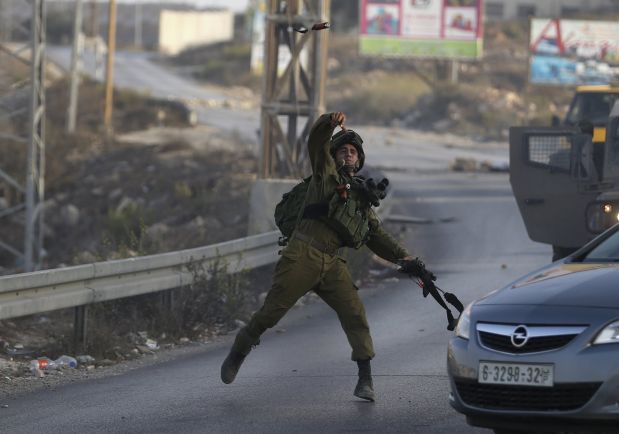 An Israeli soldier throws a sound grenade towards Palestinians during clashes near the Jewish settlement of Bet El, near the occupied West Bank city of Ramallah October 4, 2015. REUTERS/Mohamad Torokman
