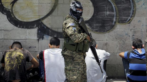 A Salvadoran army soldier watches over a group of suspected members of the Barrio 18 gang, after an attack, in San Salvador April 20, 2015. Three salvadoran soldiers were killed in the last 48 hours after the death of nine Barrio 18 gang members in an army operation this weekend. REUTERS/Jose Cabezas TPX IMAGES OF THE DAY
