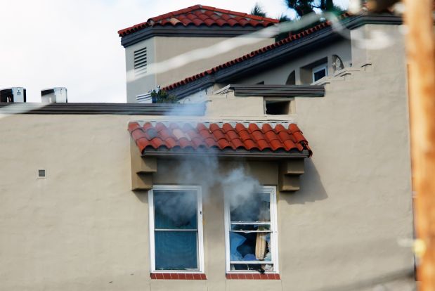 Tear gas streams from broken windows Windows broken at the scene of a shooting with a suspect with a high-powered rifle in the Bankers Hills section of San Diego, California November 4, 2015. San Diego police SWAT team members surrounded an apartment on Wednesday, where they said a man armed with a high-powered rifle was 