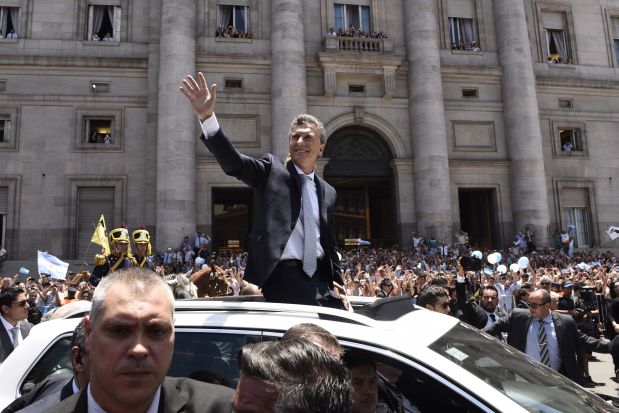 Mauricio Macri waves as he rides in an open top car towards the presidential palace after he was sworn as Argentina's new president in Buenos Aires, Argentina, Thursday, Dec. 10, 2015. Macri, the former mayor of Buenos Aires who hails from one of Argentina's richest families, took the oath of office in Congress in front of legislators, several Latin American heads of state and other dignitaries, including former Spanish King Juan Carlos I. (AP Photo/Maria Eugenia Cerutti)