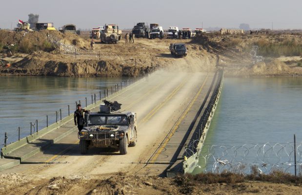Iraqi security forces cross a bridge built by corps of Engineers over the Euphrates River as Islamic State destroyed all the bridges leading to central Ramadi to block Iraqi security forces from moving forward in Ramadi, 70 miles (115 kilometers) west of Baghdad, Iraq, Tuesday, Dec. 22, 2015. Iraqi forces on Tuesday reported progress in the military operation to retake the city of Ramadi from the Islamic State group, saying they made the most significant incursion into the city since it fell to the militants in May. (AP Photo/Osama Sami)