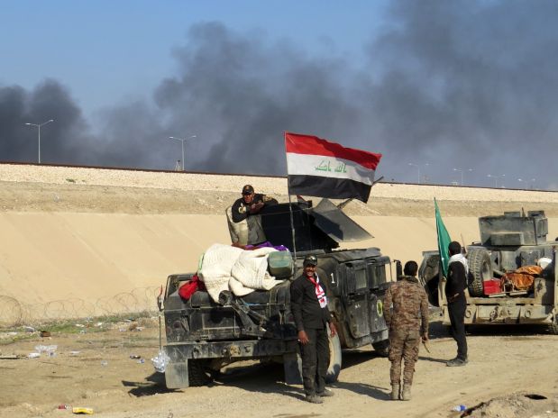 Iraqi pro-government forces stand next to armored vehicles as they take position in al-Aramil area, south of the Anbar province's capital Ramadi, during military operations on December 22, 2015. Iraqi security forces advanced into the centre of the city for a final push aimed at retaking the city they lost to the Islamic State jihadist group in May 2015.   AFP PHOTO / STR