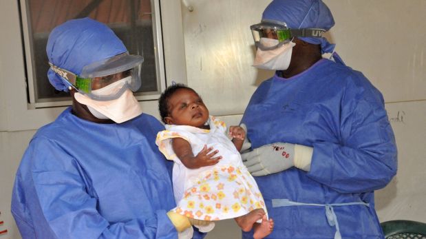 Medical workers present Noubia (C), the last known patient to contract Ebola in Guinea, during her release from a Doctors Without Borders treatment center in Conakry on November 28, 2015. The 34-day-old baby, officially declared treated on November 16, was presented by personal from the treatment center, with applause, during an emotional ceremony, in the presence of her family. AFP PHOTO / CELLOU BINANI