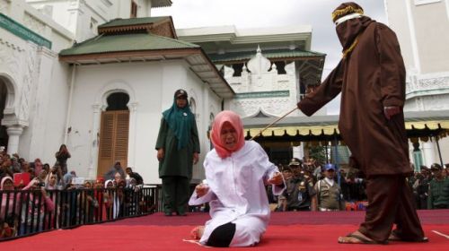 Nur Elita, an Acehnese woman, screams during caning as part of her sentence in the courtyard of Baiturrahman mosque in Banda Aceh, Indonesia's Aceh province December 28, 2015. Nur Elita  received five strokes of the cane for having pre-marital sex with her boyfriend, according to local media. Aceh is the only province in Indonesia, the world's most populous Muslim country, where Islamic law is implemented, according to local media. REUTERS/Junaidi Hanafiah        EDITORIAL USE ONLY. NO RESALES. NO ARCHIVE      TPX IMAGES OF THE DAY