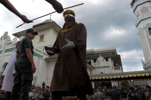 A member of the sharia police receives a cane as officials conduct punishment based on Islamic sharia law in Banda Aceh on December 28, 2015.  Aceh is the only province of Indonesia enforcing the Islamic Sharia law and offenders are punished by public caning.  / AFP / CHAIDEER MAHYUDDIN