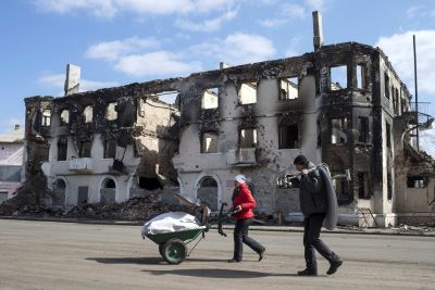 People walk past a destroyed building in the town of Vuhlehirsk, north-east from Donetsk, March 8, 2015. REUTERS/Marko Djurica (UKRAINE - Tags: POLITICS CIVIL UNREST CONFLICT TPX IMAGES OF THE DAY)
