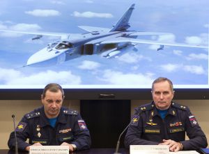 Col. Nikolai Primak, left, head of Russian investigation commission, and Lt-Gen. Sergei Bainetov speak about the Russian Su-24 bomber, seen behind, which was shot down by Turkey at the border with Syria on Nov. 24, saying it violated its airspace for 17 seconds despite repeated warnings, in Moscow on Monday, Dec. 21, 2015.  Bainetov, a deputy head of the Russian military's flight safety service, said Monday an inspection of the recorder has revealed that 13 of 16 microchips on its data board are nearly ruined and the remaining three are damaged.  (AP Photo/Pavel Golovkin)