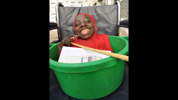 A physically challenged girl smiles she is kept in a basin on her wheelchair to seek alms from people on the street in Kano, Nigeria December 30, 2015. The girl has suffered from her condition since birth. Picture taken December 30.  REUTERS/Stringer        EDITORIAL USE ONLY. NO RESALES. NO ARCHIVE