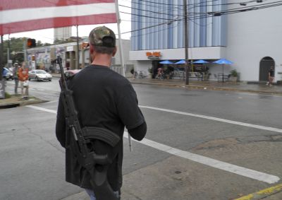 A pro-gun advocate walks down the street outside the University of Texas ahead of a 'mock mass shooting' event where they used cardboard cut-outs rifles, the simulated bangs of bullets on bullhorns and doused fake victims with fake blood, in Austin, Texas in this December 12, 2015 file photo. Southern Methodist University, one of the top private colleges in Texas, on Friday said it would opt out of state law due to go into effect next year that allows people with licenses for concealed handguns to bring them on campus.    REUTERS/Jon Herskovitz/Files