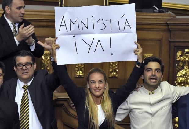 The wife of jailed Venezuelan opposition leader Leopoldo Lopez, Lilian Tintori  (C) shows a banner asking for an immediate amnesty for political prisoners at the Venezuelan parliament in Caracas, on January 5, 2016.  Venezuela's President Nicolas Maduro ordered the security forces to ensure the swearing-in of a new opposition-dominated legislature passes off peacefully Tuesday, after calls for rallies raised fears of unrest. AFP PHOTO/JUAN BARRETO