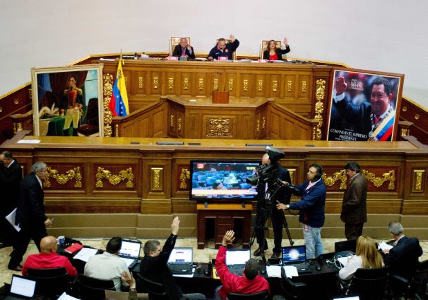 Members of the National Assembly vote an article of the national budget during a session in Caracas, Venezuela, Thursday, Dec. 10, 2015. Venezuela's ruling socialist party is set to rush through a series of appointments before the opposition takes over congress next month with promises to revive what it calls a moribund institution. The legislature was expected to name 12 Supreme Court justices Thursday during a final session, filling vacancies left by a group of judges who requested early retirement. (AP Photo/Fernando Llano)