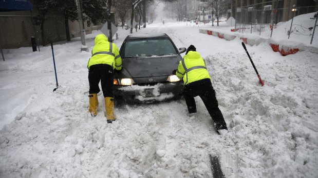 Workers help free a passing motorist from the snow on L Street in downtown Washington, Saturday, Jan. 23, 2016. Millions of people awoke Saturday to heavy snow outside their doorsteps, strong winds that threatened to increase through the weekend, and largely empty roads as residents from the South to the Northeast heeded warnings to hunker down inside while a mammoth storm barreled across a large swath of the country. (AP Photo/Gerald Herbert)