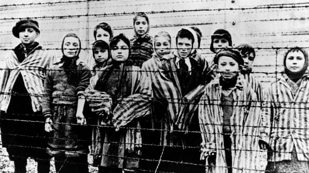 FILE - In this file photo taken just after the liberation by the Soviet army in January, 1945, shows a group of children wearing concentration camp uniforms including Martha Weiss who was ten years-old, 6th from right, at the time behind barbed wire fencing in the Oswiecim (Auschwitz) Nazi concentration camp. A 94-year-old former SS guard at the Auschwitz death camp is going on trial Thursday, Feb. 11, 2016 on 170,000 counts of accessory to murder, the first of up to four cases being brought to court this year in an 11th-hour push by German prosecutors to punish Nazi war crimes. Reinhold Hanning is accused of serving as an SS Unterscharfuehrer _ similar to a sergeant _ in Auschwitz from January 1943 to June 1944, a time when hundreds of thousands of Hungarian Jews were brought to the camp in cattle cars and were gassed to death.   (AP Photo)