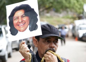 A man holds up a cutout portrait of slain Honduran indigenous leader and environmentalist Berta Caceres outside the coroners office in Tegucigalpa, Honduras, Thursday, March 3, 2016. Caceres, a Lenca indigenous activist who won the 2015 Goldman Environmental Prize for her role in fighting a dam project, had previously complained of receiving death threats from police, soldiers and local landowners because of her work. (AP Photo/Fernando Antonio)