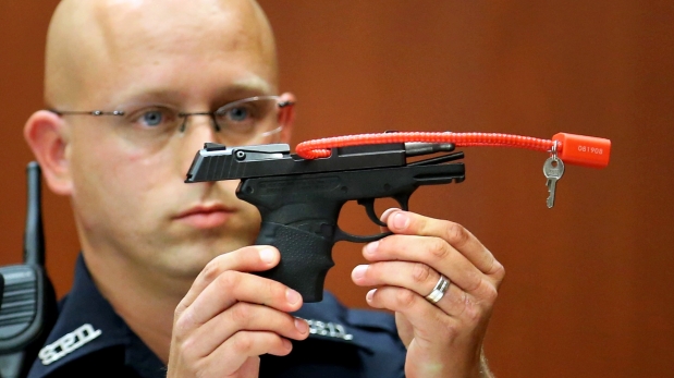 FILE- In this June 28, 2013, file photo, Sanford police officer Timothy Smith holds up the gun that was used to kill Trayvon Martin, while testifying in the George Zimmerman trial, in Seminole circuit court in Sanford, Fla. The pistol former neighborhood watch volunteer Zimmerman used in the fatal shooting of Martin is going up for auction online. (AP Photo/Orlando Sentinel, Joe Burbank, Pool, File)