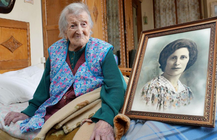 Emma Morano poses next to a picture depicting her where she was young, in Verbania, Italy, Friday, May 13, 2016. Surrounded by relatives and neighbors, Emma Morano greeted with a smile Friday the news that she, at 115 years of age, is now the oldest person in the world. Not only that, but she is believed to be the last surviving person in the world who was born in the 1800s, coming into the world on Nov. 29, 1899. That?s just 4 and a half months after Susannah Mushatt Jones, who died Thursday in New York at the age of 116. (Antonino Di Marco/ANSA via AP)