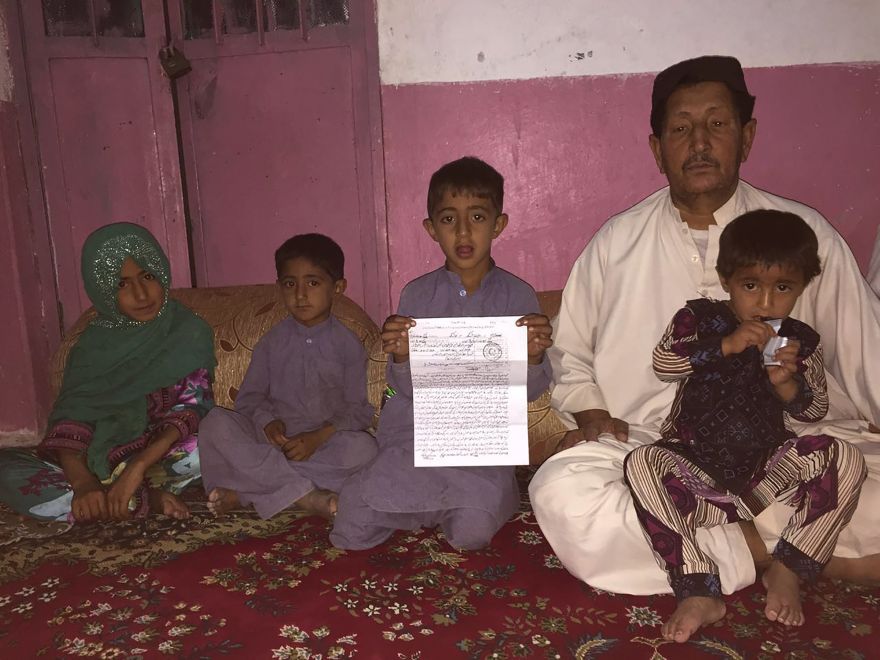 The son of Mohammad Azam, a Pakistani driver who was killed alongside Afghan Taliban's slain chief Mullah Akthar Mansour in a US drone strike, holds a copy of the charges pressed against US officials over the death of his father, as he poses with his siblings and uncle Mohammad Qasim (R), Azam's brother, at Qasim's residence in the Pakistan-Iran border town of Taftan on May 30, 2016. The brother of a man who was killed alongside the Taliban's slain chief Mullah Akthar Mansour in an American drone strike in southwest Pakistan is pressing murder and terrorism charges against US officials, police said on May 30. Mansour was travelling by car near the town of Ahmad Wal on May 21 when he was killed, a major blow to the Islamist group that has been waging a guerilla war in Afghanistan since being toppled from power in 2001. / AFP / ALI RAZA