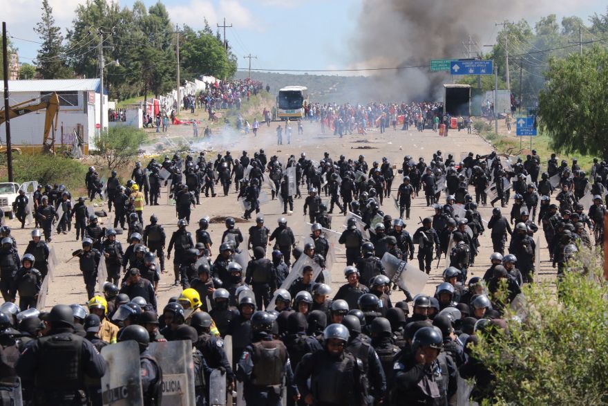 Riot police are forced to fall back as they battle with protesting teachers who were blocking a federal highway in the state of Oaxaca, near the town of Nochixtlan, Mexico, Sunday, June 19, 2016. The teachers are protesting against plans to overhaul the country's education system which include federally mandated teacher evaluations. (AP Photo/Luis Alberto Cruz Hernandez)