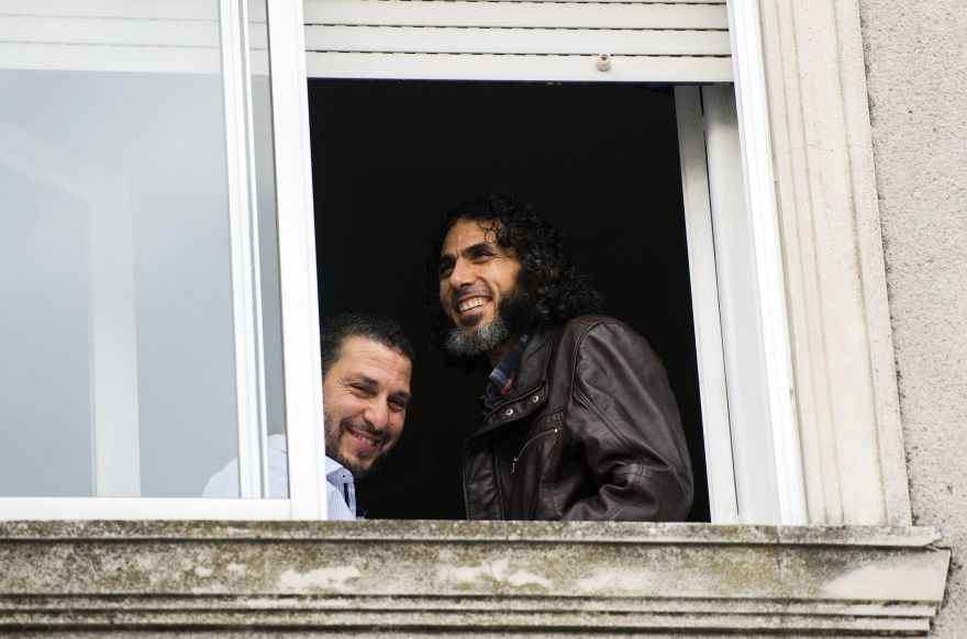FILE - In this June 5, 2015 file photo, Abu Wa'el Dhiab, from Syria, right, and Adel bin Muhammad El Ouerghi, of Tunisia, both freed Guantanamo Bay detainees, stand next to the window of their shared home in Montevideo, Uruguay. Uruguayan authorities said Friday, June 17, 2016, Dhiab traveled legally to neighboring Brazil. The clarification comes amid reports that he had fled Uruguay in violation of his refugee status in the small South American nation. Uruguay resettled Dhiab and 5 other former detainees in late 2014. (AP Photo/Matilde Campodonico, File)