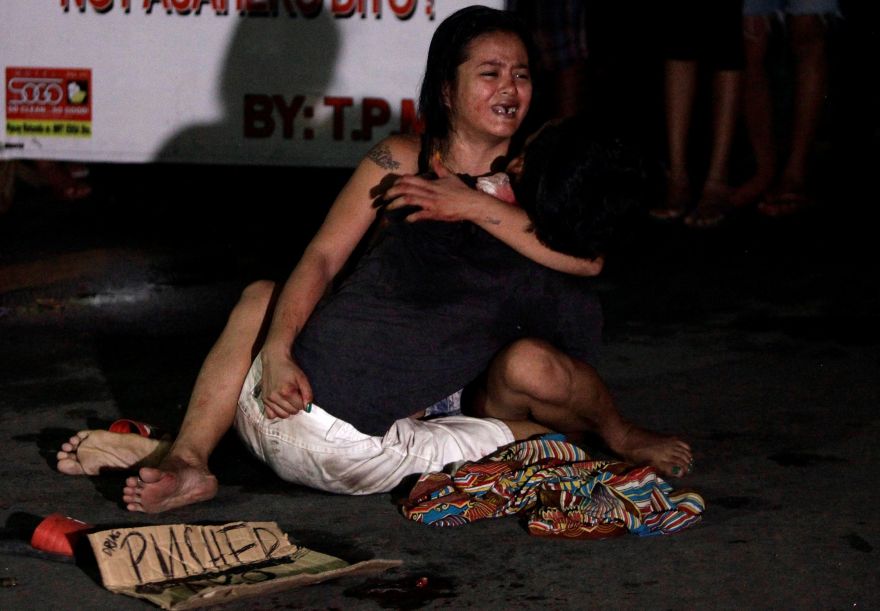 ATTENTION EDITORS - VISUAL COVERAGE OF SCENES OF INJURY OR DEATHA woman cradles the body of her husband, who was killed on a street by a vigilante group, according to police, in a spate of drug related killings in Pasay city, Metro Manila, Philippines July 23, 2016. A sign on a cardboard found near the body reads: 