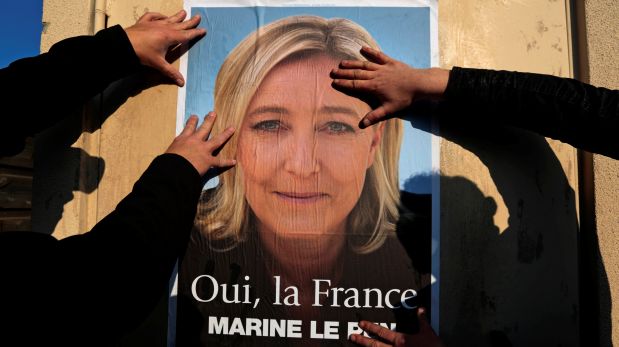 Supporters paste a poster of Marine Le Pen, France's National Front leader, on a wall before a political rally for local elections in Frejus, France March 18, 2014.REUTERS/Eric Gaillard/File Photo