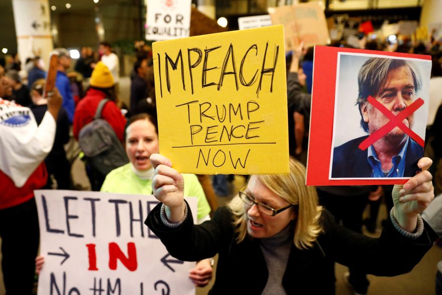 A woman holds signs against Steve Bannon and encouraging the impeachment of Trump and Pence during a protest of Donald Trump's travel ban from Muslim majority countries at the International terminal at Los Angeles International Airport (LAX) in Los Angeles, California, U.S., January 28, 2017.  REUTERS/Patrick T. Fallon