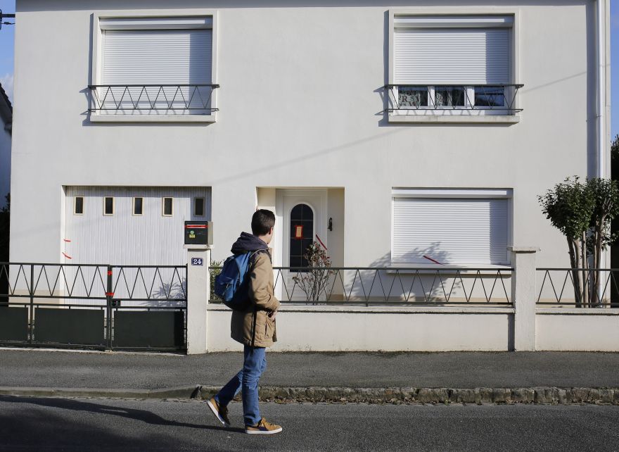 This photo dated Tuesday, Feb. 28, 2017 shows a boy passing by the house belonging to the missing Troadec family in Orvault, near Nantes, western France. Forensics officers locked down a neighborhood in western France on Wednesday, searching for traces of a family that disappeared, leaving behind a bloody cell phone, stripped beds and a home where 