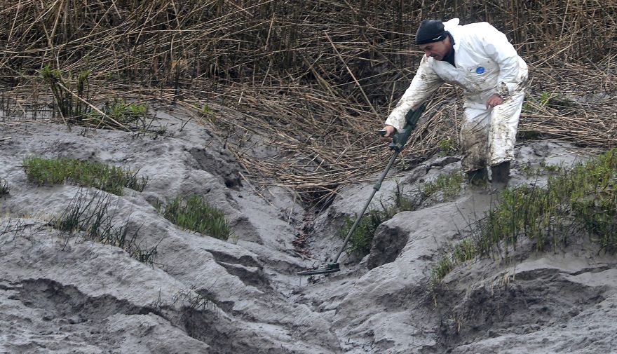 A police officer searches on March 9, 2017 on the swampy bank of the river Aulne near the Caouissin's house in Pont-de-Buis-l?s-Quimerch, western of France. Investigators on March 8, found body parts at the home in northwest France of Hubert Caouissi, the man who has confessed to killing four relatives with a crowbar, the prosecutor in the case said. The mother of Pascal Troadec, one of the four victims of Hubert Caouissin, and that of Lydie, the companion of the supposed assassin, explains that the treasure discovered by her late husband is at the origin of the tragedy, in an interview with  French newpapers Le Parisien on March 9, 2017. / AFP / FRED TANNEAU